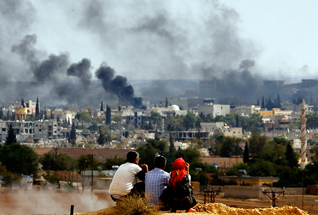 Курдские беженцы смотрят на атакуемый боевиками ИГ город Кобани. 26 октября 2014