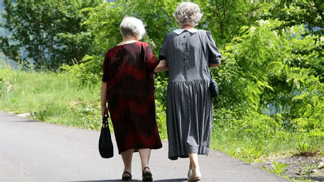 Две пожилые женщины идут по парку