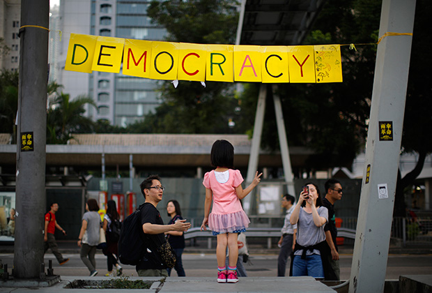 Девочка позирует возле лагеря протестующих в Гонконге. 11 октября 2014